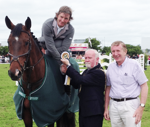 Mark Duffy on Glenomra Cocoa (ISH) presented with the 7 Year-Old winner's rosette by mayor of Galway Donal Lyons and Patrick Wall, Chairman of Horse Sport Ireland